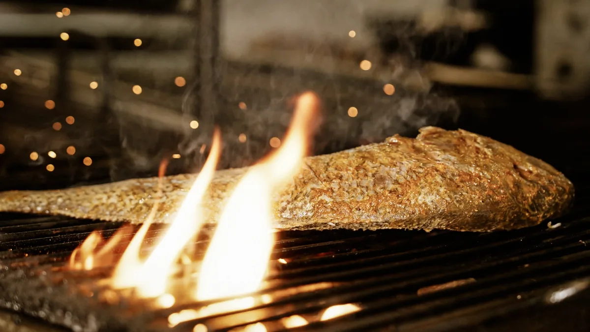 Whole croaker cooking over the charcoal grill